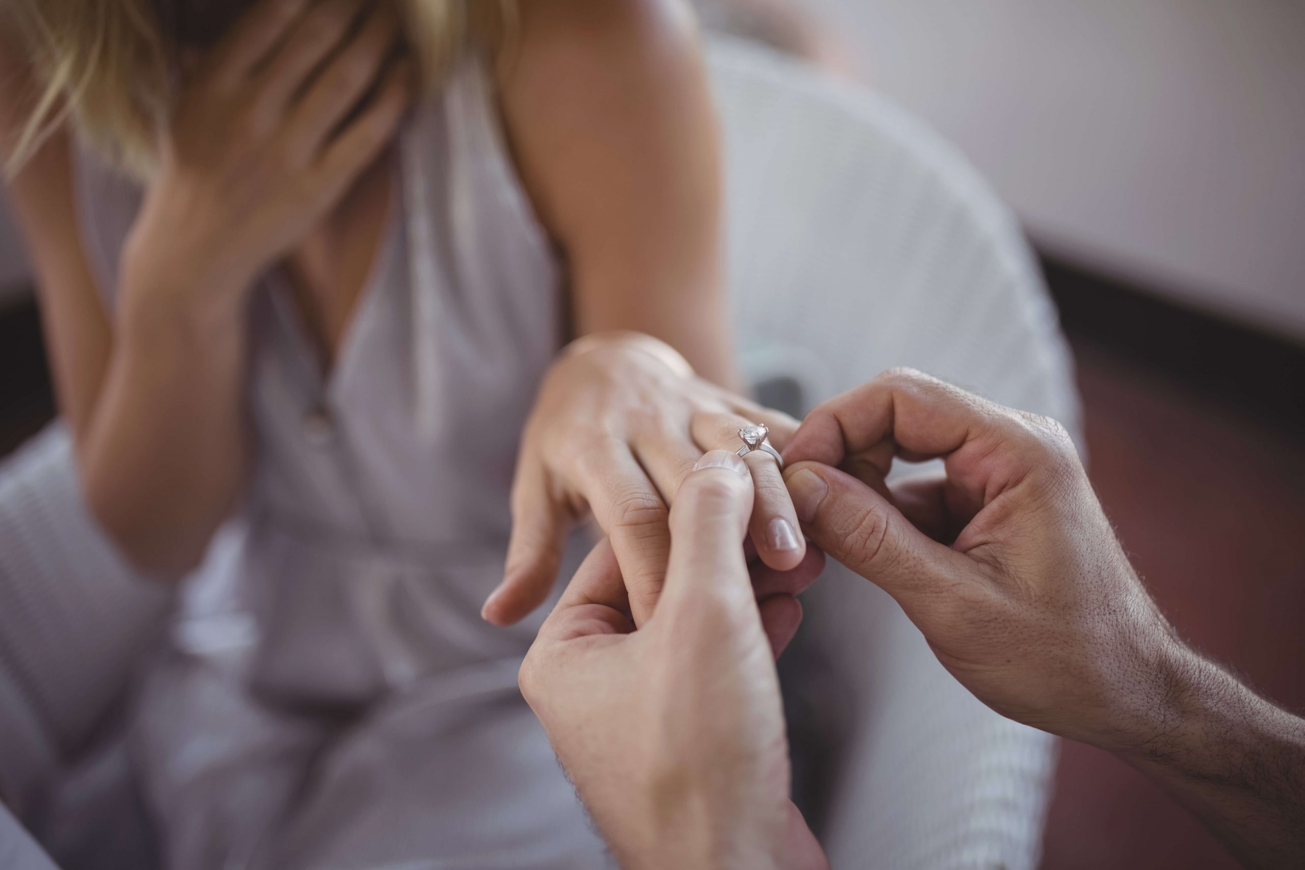 man putting diamond ring on woman's finger 