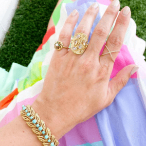 turquoise and gold bracelet and gold rings on model with colorful background