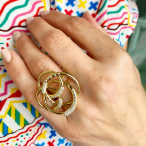 gold and diamond circle ring on model with colorful background