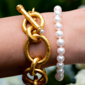gold link bracelet and pearl bracelet on model