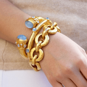 gold link bracelets and gold bangles with blue stones on model