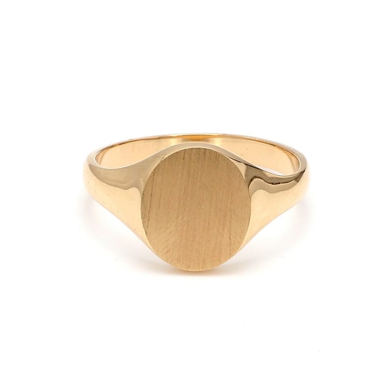 Front view of ring. A polished yellow gold band expands towards the top as it meets the brushed, oval face of this signet ring.