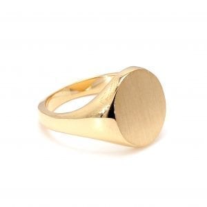 45 degree angle of ring. A 14k yellow gold signet ring has an oval face and is finished with a brushed texture. It is attached to a polished yellow gold shank.