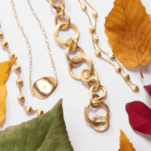 4 gold necklaces on fall leaf background
