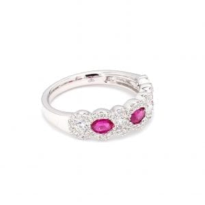 45 degree angle of ring. Three oval cut rubies alternate with round brilliant cut diamonds along the front half of this band with pave diamond scalloped edges.