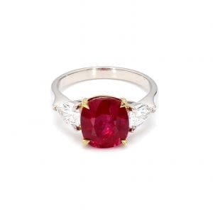 Front view of ring. A simple white gold band is decorated by a center cushion cut burma ruby set in 18k yellow gold with a pear cut diamond on either side.