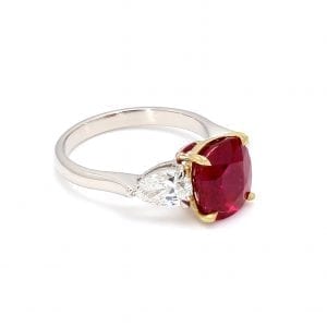 45 degree angle of ring. A simple white gold band is decorated by a center cushion cut burma ruby set in 18k yellow gold with a pear cut diamond on either side.