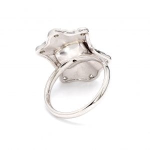 Back view of ring. A simple white gold band is attached to a burst/ ballerina style mounting with no cutouts, solid back. Mounting resembles a shield.