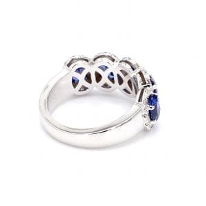 135 degree angle of ring. A simple white gold band leads to a five stone setting that has five oval cut sapphires surrounded by pave diamond halos.