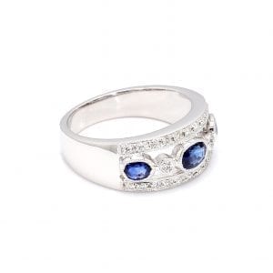 Side view of this ring with a thick white gold band, the center front has cut outs with a row of alternating bezel set oval sapphires and round diamonds. The top and bottom bands of the front half of this ring is accented by pave diamonds.