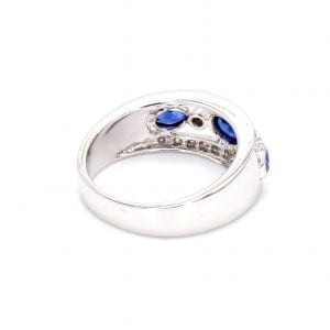 135 degree angle of this ring with a thick white gold band with cutouts in the center and cutouts in the metal from the bezel set row of alternating oval sapphires and round diamonds. Indents in the top and bottom band of the front half of this ring where the pave diamonds are set.