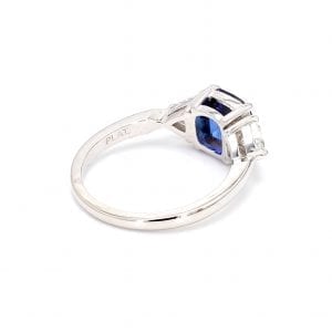 135 degree angle of ring. A simple white gold band leads to a three stone setting with a cushion cut sapphire in the center and a trillion cut diamond on either side.
