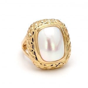 A front view of this ring shows a center elongated oval cut mabe pearl in a honeycomb detailed setting, attached to a yellow gold shank with split sides.