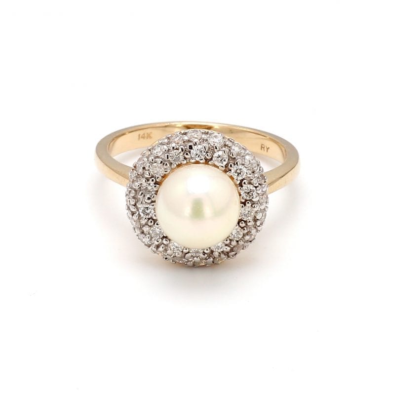 This ring showcases a center round, white pearl and is encircled by a pave diamond halo, attached to a simple 14k yellow gold band.