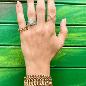 gold and diamond rings and bracelets on model with green background