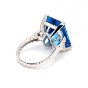 135 degree angle of ring. A simple white gold shank accented with two baguette diamonds on each shoulder attached to a large setting for a octagonal step-cut blue topaz center.