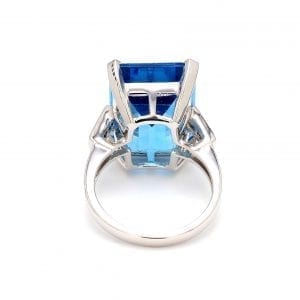 Back view of ring. A simple white gold shank accented with two baguette diamonds on each shoulder attached to a large setting for a octagonal step-cut blue topaz center.