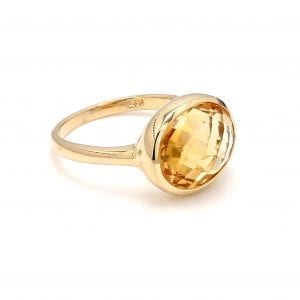 45 degree angle of ring. A polished yellow gold shank boasts a briolette cut oval citrine, set east to west.