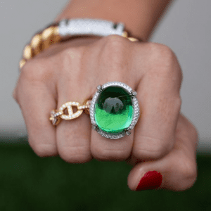 green stone, diamond, and gold rings on model