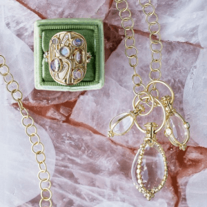 gold and colored stone jewelry on pink textured background