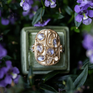 gold ring with purple stones on green and purple floral background
