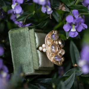 gold ring with purple stones on green and purple background