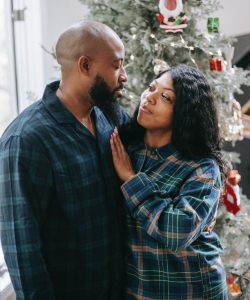 Couple looking at each other by a Christmas tree.