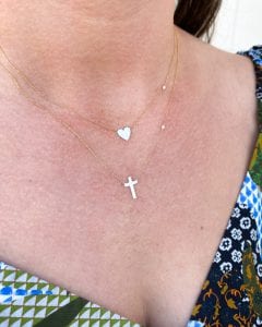 Woman's chest wearing gold heart and cross necklaces.