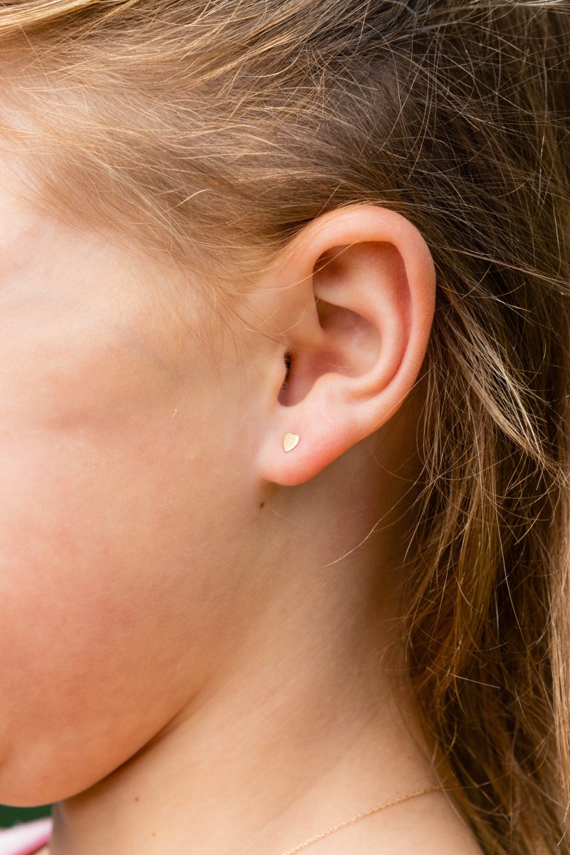 Premium Photo  Ear piercing in a child  a girl shows an earring in her  ear made of a medical alloy white background portrait of a girl with a  mole on
